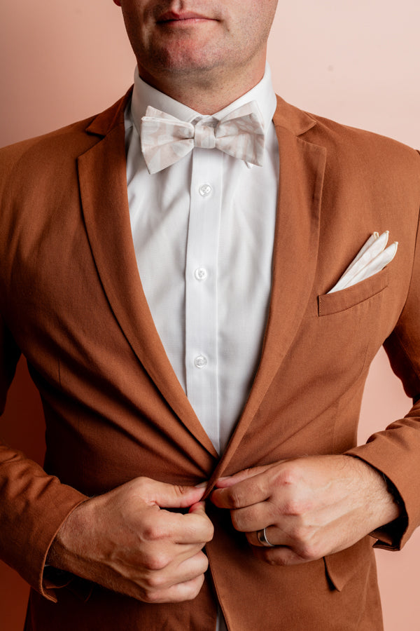 Modern and stylish bow tie featuring a detailed cut-out flowers print inspired by Australian native flowers in an abstract, minimalist style with sand and white hues