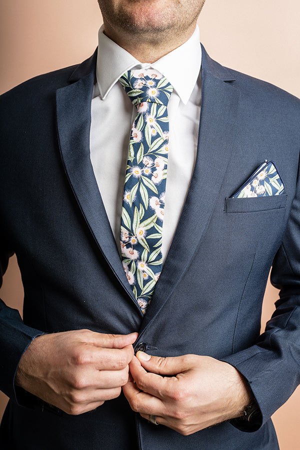100% cotton tie with flowering gum motif, showcasing vibrant pink blooms against a subtle blue backdrop, designed for sophisticated looks