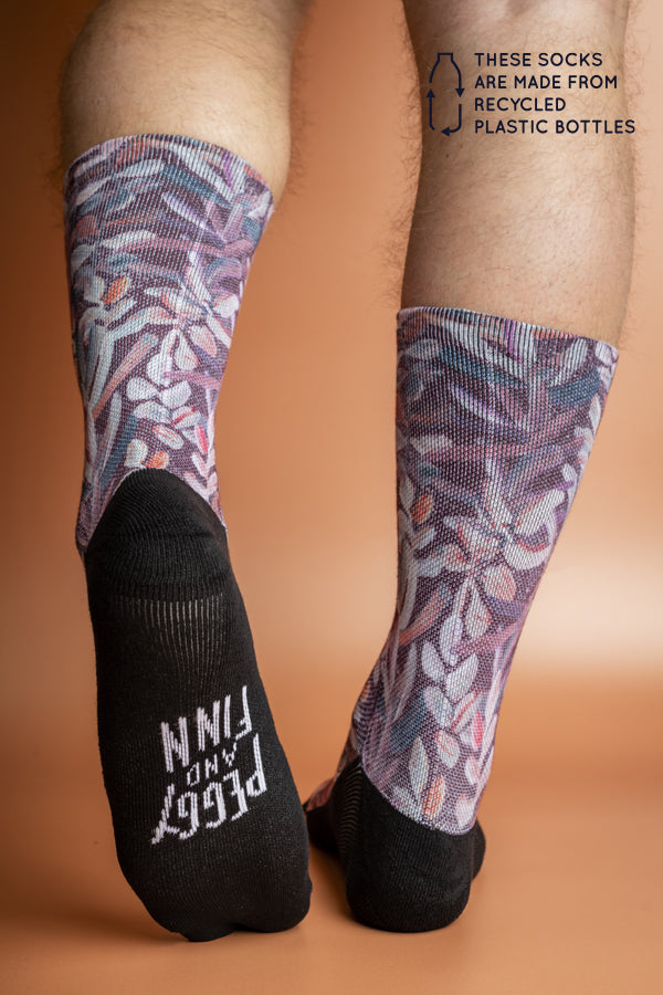 Recycled polyester socks showcasing an intricate Protea flower design in shades of red and pink on a deep burgundy background